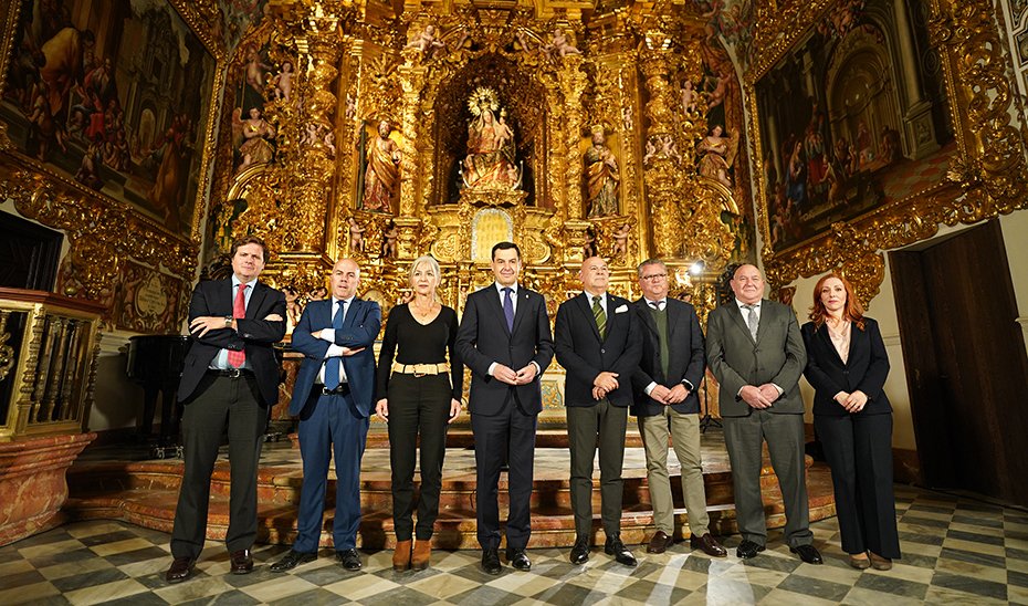 El presidente de la Junta, Juanma Moreno, junto a la consejera de Cultura y Deporte, Patricia del Pozo, y los miembros de la directiva de la Asociación Gremial Sevillana de Arte Sacro, en la capilla del Palacio de San Telmo.