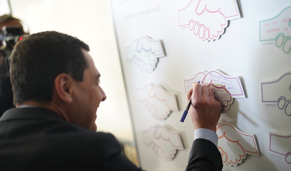 Juanma Moreno signs a panel at the congress.